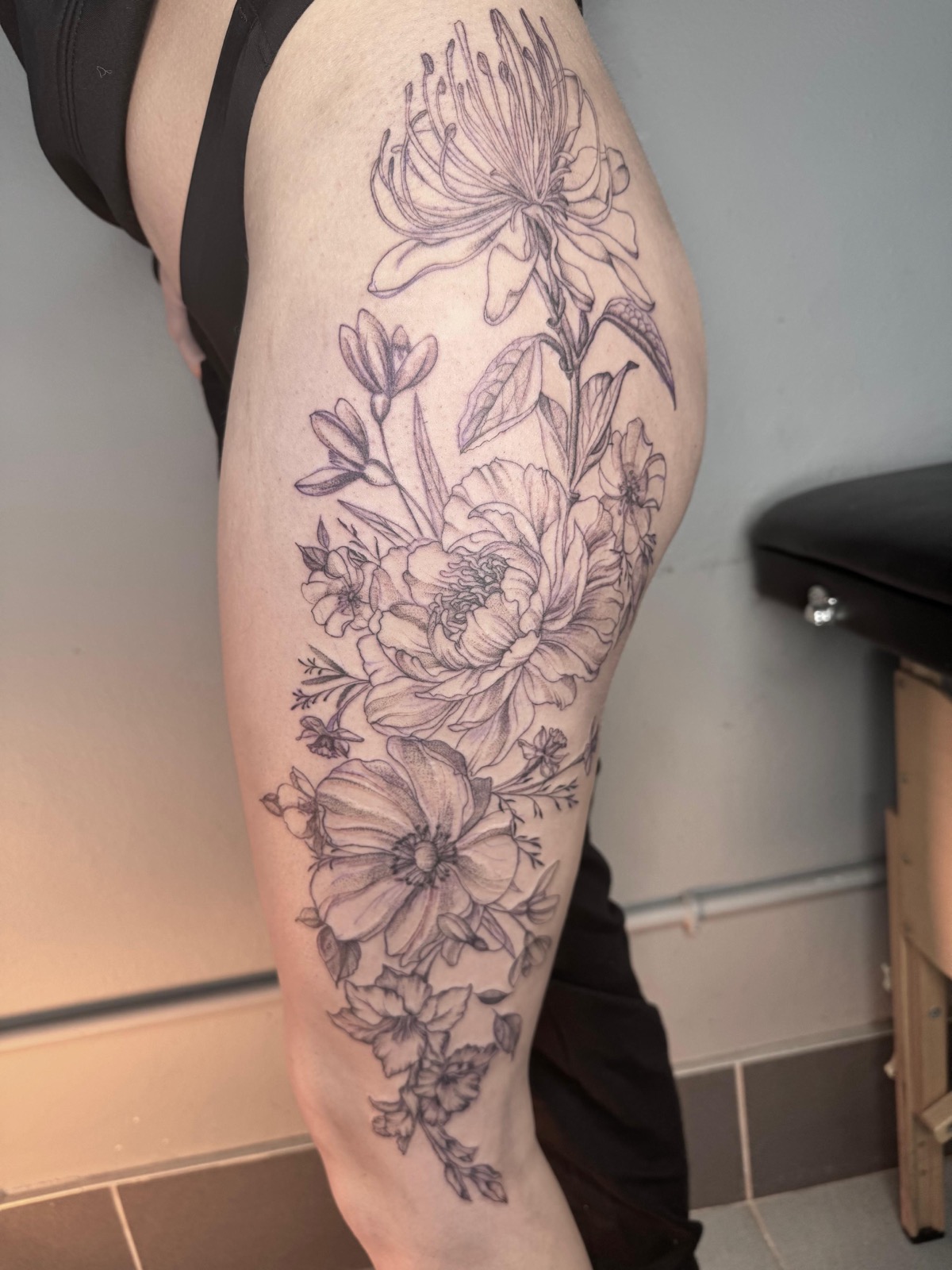 Fineline floral piece, peonies and daisies running from hip to thigh
