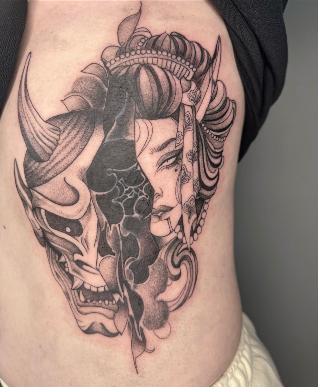 Micro-realism tattoo combining a geisha portrait and a Hannya mask on the torso